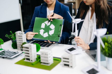 Foto de Equipo de negocios planeando y discutiendo sobre energía alternativa con símbolo de reciclaje en la sala de reuniones de la oficina. Empresa ecológica y concepto de medio ambiente de energía solar - Imagen libre de derechos