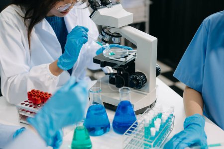 Photo for Team scientists conducting research investigations in a medical laboratory, a researcher in the foreground is using a microscope in laboratory for medicine. - Royalty Free Image