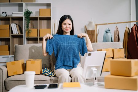 Foto de Concepto de blogger de moda, Joven mujer asiática vendiendo ropa en streaming de video usando tableta. Puesta en marcha de pequeñas empresas PYME - Imagen libre de derechos