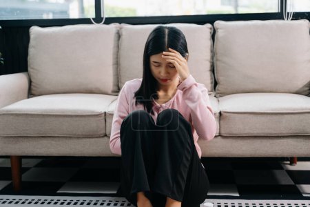 Photo for Asian woman feeling depression sitting on the floor at the sofa in the house - Royalty Free Image