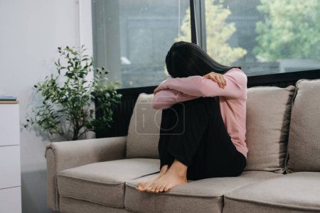 Photo for Asian woman feeling depression sitting on the sofa in the house - Royalty Free Image