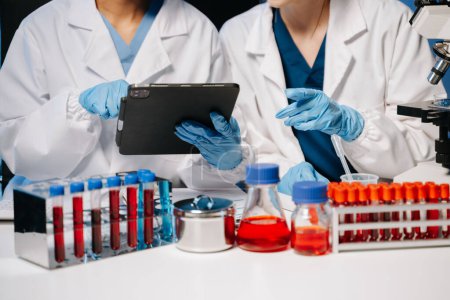 Jóvenes científicos que llevan a cabo investigaciones en un laboratorio médico, investigadores que utilizan un microscopio y una tableta digital en el laboratorio de medicina.  