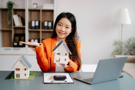 Real estate broker agent presenting  home model. Businesswoman consult to customer of concerning mortgage loan offer in office 