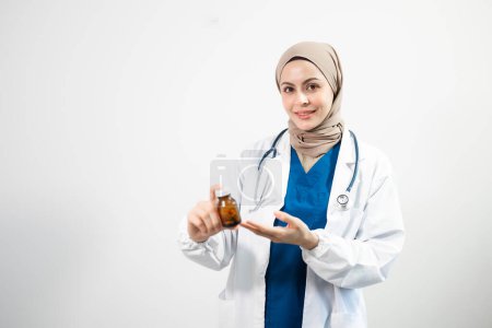 Photo for Muslim Arab person. Female doctor holding bottle with pills on isolated white background in studio - Royalty Free Image
