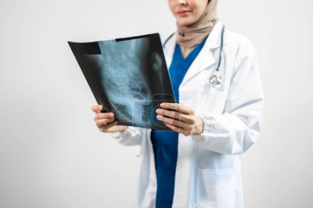 Téléchargez les photos : Arabe musulman. Médecin femme tenant une radiographie sur fond blanc isolé en studio - en image libre de droit