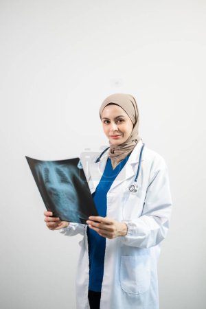 Téléchargez les photos : Arabe musulman. Médecin femme tenant une radiographie sur fond blanc isolé en studio - en image libre de droit