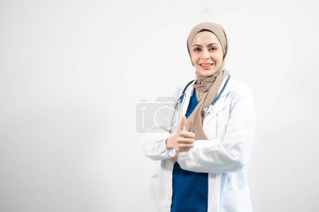 Téléchargez les photos : Arabe musulman. Femme médecin montrant pouces vers le haut sur fond blanc isolé en studio - en image libre de droit