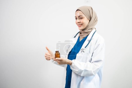 Téléchargez les photos : Arabe musulman. Femme médecin tenant bouteille avec des pilules sur fond blanc isolé en studio - en image libre de droit