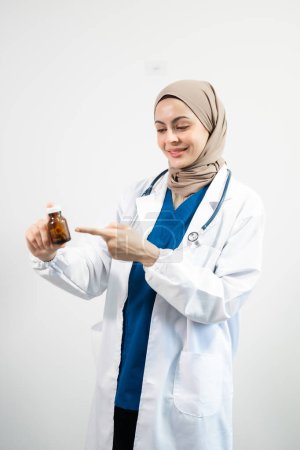 Téléchargez les photos : Arabe musulman. Femme médecin tenant bouteille avec des pilules sur fond blanc isolé en studio - en image libre de droit