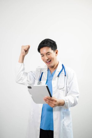 Téléchargez les photos : Médecin homme portant un manteau blanc et un stéthoscope à l'aide d'une tablette numérique sur fond blanc isolé - en image libre de droit