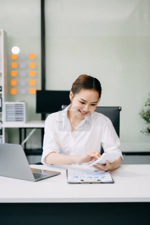 Téléchargez les photos : Succès asiatique Businesswoman Analyse des finances sur calculatrice au bureau moderne - en image libre de droit