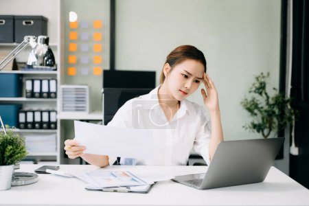 Photo for Asian woman feeling migraine head strain.Overworked businesswoman tired after work on laptop computer at office - Royalty Free Image