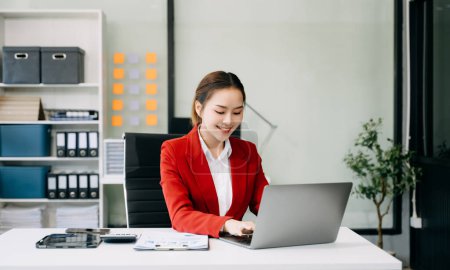 Téléchargez les photos : Succès asiatique Businesswoman travaillant sur ordinateur portable au bureau moderne - en image libre de droit