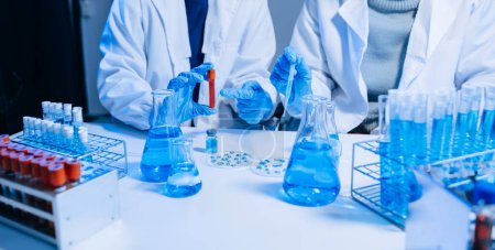 Photo for Two Scientists mixing chemical liquids in the chemistry lab. Researchers working in the chemical laboratory and new chemical substances - Royalty Free Image