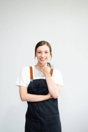 Téléchargez les photos : Femme caucasienne entrepreneur dans tablier ou propriétaire de magasin tenant la main sur le menton Isolé sur fond blanc - en image libre de droit