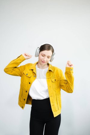 Téléchargez les photos : Jeune femme caucasienne 20s porte des vêtements décontractés dansant dans les écouteurs, écartant les mains isolées sur fond blanc - en image libre de droit