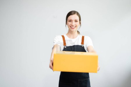 Téléchargez les photos : Femme caucasienne souriant et tenant paquet boîte de colis isolé sur fond blanc, livraison messager et concept de service d'expédition - en image libre de droit