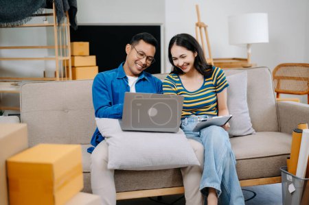 Photo for Asian young attractive couple man and woman use tablet and laptop for online shopping furniture, to decorate new house. Young married asian moving into new home - Royalty Free Image