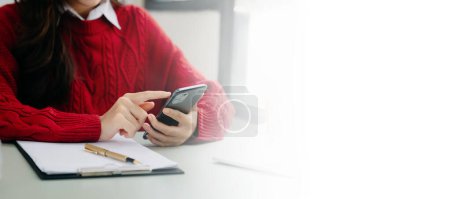 Selbstbewusste Geschäftsfrau arbeitet im modernen Büro am Smartphone