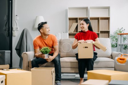 Happy asian young attractive couple man and woman with big boxes moving into a new house