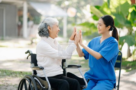Ancianos asiático senior mujer en silla de ruedas con asiático cuidadoso cuidador unir sus manos juntos en jardín
