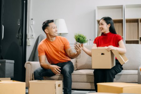 Happy asian young attractive couple man and woman with big boxes moving into a new house