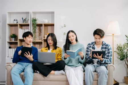 Photo for Group of young Asian college students working on project assignment, using laptop computer with digital tablet and online information at home - Royalty Free Image