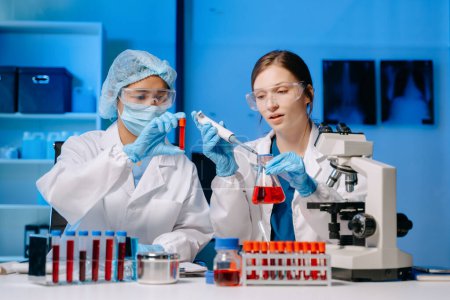 Photo for Young scientists conducting research investigations in a medical laboratory, a researchers in the foreground is using a microscope in laboratory for medicine. - Royalty Free Image