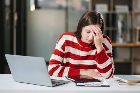 Téléchargez les photos : Femme qui ressent une migraine. Femme d'affaires surmenée travaillant sur ordinateur portable au bureau - en image libre de droit
