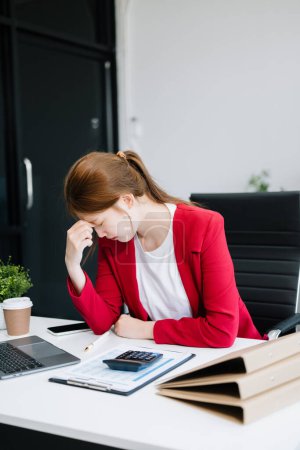 Foto de Asiática mujer de negocios sintiendo migraña cabeza strain.Overworked ejecutivo cansado de trabajar en el ordenador portátil en la oficina - Imagen libre de derechos