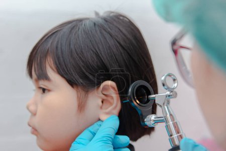 Photo for A doctor uses an ostomoscope to examine a child's ears. - Royalty Free Image