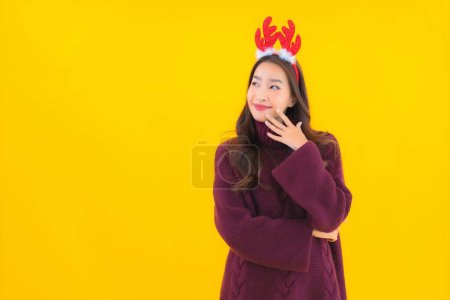 Porträt schöne junge asiatische Frau tragen Weihnachtsdekoration Thema auf gelbem isolierten Hintergrund