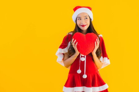 Foto de Retrato hermoso joven asiático navidad ropa y sombrero sonrisa feliz con forma de corazón en amarillo aislado fondo - Imagen libre de derechos