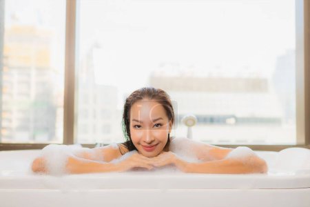 Téléchargez les photos : Portrait belle jeune femme asiatique se détendre profiter prendre un bain à la baignoire dans la salle de bain intérieure - en image libre de droit