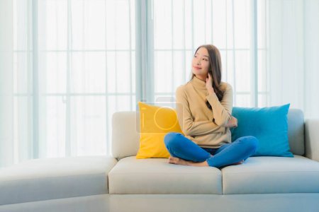 Foto de Retrato hermosa joven mujer asiática relajarse ocio disfrutar en sofá en sala de estar área interior - Imagen libre de derechos