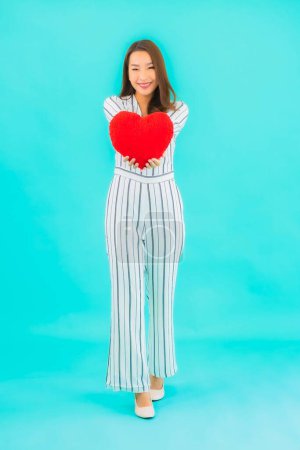 Photo for Portrait beautiful young asian woman with heart pillow shape on blue background - Royalty Free Image