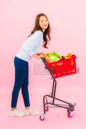 Photo for Portrait beautiful young asian woman with fruit vegetable and grocery in basket on pink isolated background - Royalty Free Image