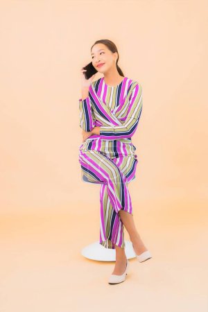 Téléchargez les photos : Portrait belle jeune femme asiatique utiliser téléphone mobile intelligent sur fond isolé couleur - en image libre de droit