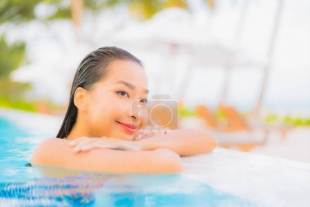 Téléchargez les photos : Portrait belle jeune femme asiatique se détendre loisirs autour de la piscine extérieure avec mer océan plage - en image libre de droit