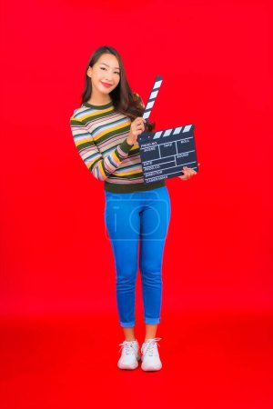 Téléchargez les photos : Portrait belle jeune femme asiatique avec film ardoise coupe sur fond rouge isolé - en image libre de droit