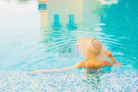 Portrait belle jeune femme asiatique relax sourire profiter des loisirs autour de la piscine en hôtel station balnéaire en vacances