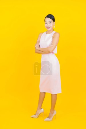 Foto de Retrato hermosa joven mujer asiática sonrisa con acción sobre fondo de color amarillo - Imagen libre de derechos