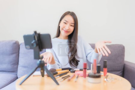 Téléchargez les photos : Portrait belle jeune femme asiatique examen cosmétique maquillage en ligne à la maison - en image libre de droit