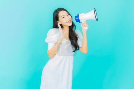 Téléchargez les photos : Portrait belle jeune femme asiatique sourire avec mégaphone sur fond de couleur - en image libre de droit