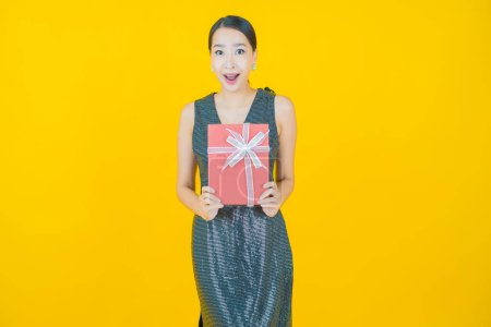 Téléchargez les photos : Portrait belle jeune femme asiatique sourire avec boîte cadeau rouge sur fond de couleur - en image libre de droit