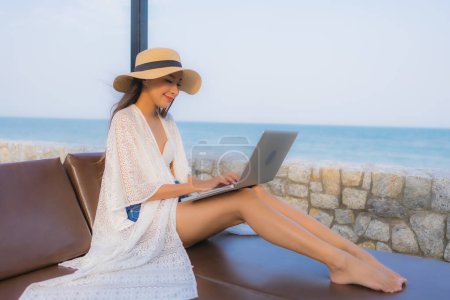 Photo for Portrait young asian woman using laptop computer for work around beach sea ocean - Royalty Free Image