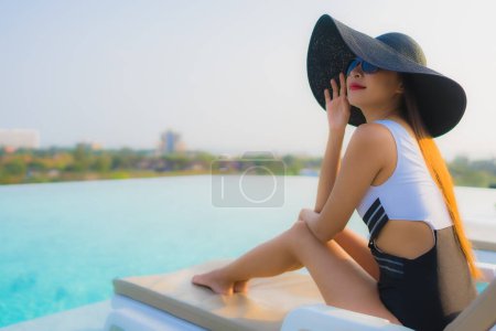 Téléchargez les photos : Portrait belle jeune femme asiatique sourire heureux se détendre autour de la piscine extérieure dans la station hôtelière pour des vacances de voyage - en image libre de droit