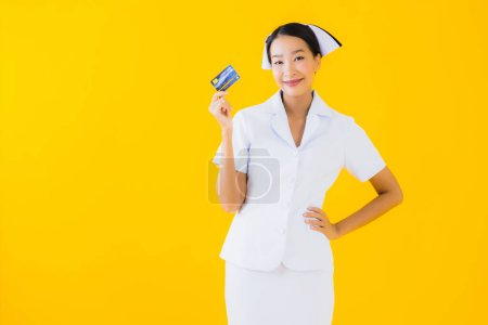 Photo for Portrait beautiful young asian woman thai nurse with credit card on yellow isolated background - Royalty Free Image