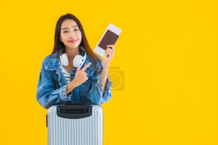 Foto de Retrato hermosa joven mujer asiática de viaje y ocio con bolsa de equipaje y pasaporte, tarjeta de embarque sobre fondo aislado amarillo - Imagen libre de derechos