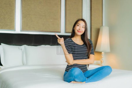Téléchargez les photos : Portrait belle jeune femme asiatique sourire se détendre sur le lit dans la chambre intérieur - en image libre de droit